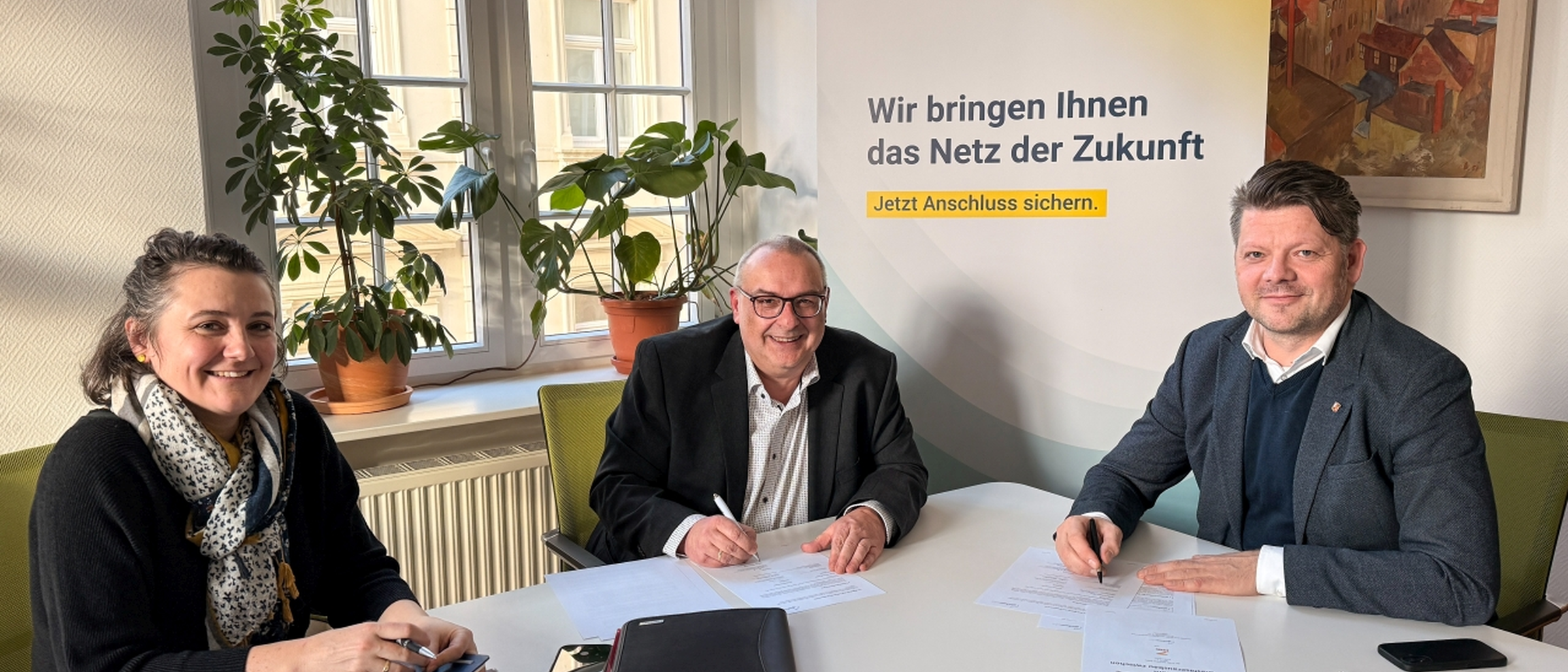 Am Tisch im Oberb&uuml;rgermeisterb&uuml;ro sitzen Wirtschaftsf&ouml;rderin Gloria Heymann, Oberb&uuml;rgermeister Zenker und Uwe Plonka vom Unternehmen GlasfaserPlus bei der Vertragsunterzeichnung